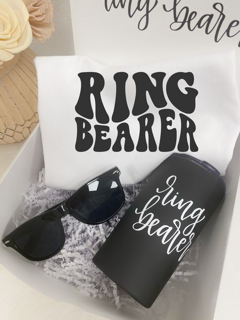 "-----DETAILS---- This listing is for a ring bearer gift set which includes:  - ONE tumbler with ring bearer design  - ONE shirt (toddler size or youth) with \"ring bearer\" design  - ONE pair of sunglasses (youth size)  - ONE box measuring 8x8x4inches with \"will you be my ring bearer\" wording on inside lid  Boxes are assembled with crinkle fill if shipping directly to recipient however if more than 1 box is ordered, boxes will ship flat and unassembled. Crinkle paper may be purchased as an add on here:  https://www.etsy.com/listing/1256031877/add-crinkle-paper-to-your-order-price-is?click_key=1ef99c0faff1e7d20decd803e53e622b749b19ce%3A1256031877&click_sum=a7744b8e&ga_search_query=Crinkle&ref=shop_items_search_1&frs=1&crt=1&sts=1 All items are customizable! Please message me with any req Ring Bearer Box Proposal, Gifts For Ring Bearer, Ring Bearer Proposal Box, Ring Bear Proposals, Will You Be My Ring Bearer Ideas, Ring Barrier, Ring Bearer Proposal Box Ideas, Ring Bear Proposal Box Ideas, Ring Barrier Proposal