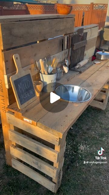 The Vintage Spoon | Mackenzie Winterton on Instagram: "DIY Pallet Mud Kitchen!  So excited about this mud kitchen! We still need to add a shelf on the bottom but the  kids absolutely love it! They are always making mud pies and potions in the summer so i wanted to make a space for them to do that and my husband help make that happen! The best part is its made out of mostly pallets and scrap wood from our deck build. I bought all the accessories at the thrift store and a couple things from the dollarstore. We are so ready for summer time over here!  #mudkitchen #montessori #letthembelittle #sahm#kids #simplejoys #momlife#yql #diy#momsofinstagram #pallet #palletprojects #diyprojects#palletmudkitchen #mudkitchen #mud" Mud Kitchen Made From Pallets, Mud Kitchen Out Of Pallets, Mud Kitchen Accessories Ideas, How To Make A Mud Kitchen, Mud Kitchen For Kids Pallets, Mud Kitchen Pallets, Kids Mud Kitchen Diy, Pallet Mud Kitchen Diy, Diy Mud Kitchen Outdoor Play