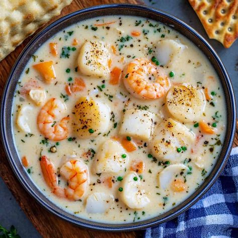 crockpot soup recipes. Seafood Chowder: A creamy seafood chowder filled with plump shrimp, scallops, and tender fish pieces. Carrot and herb garnishes add pops of color to the thick, buttery broth, making it a comforting, rich dish. Shrimp And Scallop Soup Recipes, Seafood Stew Crockpot, Cheesy Seafood Chowder, Crockpot Seafood Soup Recipes, Fish Soups And Chowders, Slow Cooker Seafood Chowder, Scallop Soup Recipes, Stuffed Seafood Soup Bread Bowl, Fish Soups And Stews