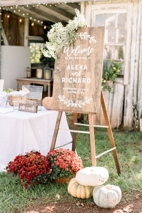 This autumnal welcome sign is adorned with a floral swag of baby's breath and seeded eucalyptus with mums and ornamental pumpkins at the base for a seasonal touch. Photographer Shannon Moffit. White Pumpkins And Eucalyptus Wedding, Mums Ceremony Decor, White Mum Wedding Decor, Mums Wedding Alter, Entryway Wedding Decor Receptions, Mums At Wedding Ceremony, Mums And Pumpkins Wedding, Mums As Wedding Decor, Fall Wedding Mums And Pumpkins