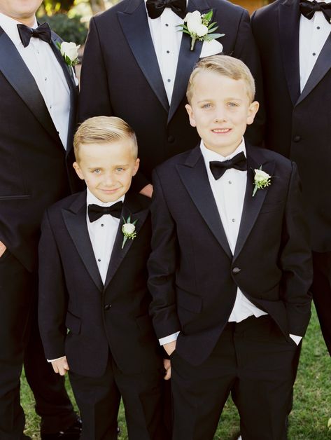 Boys in black tuxedos and bow ties Ring Bearer Black Suit, Kids Tuxedo Boys Wedding, Page Boys Wedding Outfits, Ring Bearer Outfit Black, Boys Tuxedo Wedding, Tuxedo Ideas, Dark Academia Wedding, White And Greenery Wedding