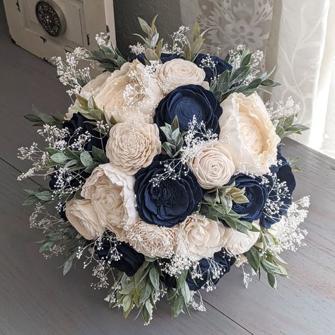 "Please Read Entire Description Before Purchase Bouquet with sola wood flowers in navy and ivory, with baby's breath and faux greenery. Flower styles can and will vary based on current inventory levels and to keep orders unique, so they are not exact duplicates. Please include your choice of stem wrap and color (color of ribbon, white or ivory lace, or twine) in the notes section. Size pictured is an extra large (approximately 10\" in diameter). Bouquets listed in the Etsy shop are not eligible for customization, aside from stem wrap.  Please contact me for rush orders. Add a one pack touch up kit here: https://www.etsy.com/listing/738967985/add-a-touch-up-kit-for-my-sola-flowers Add brooches to your bouquet here: https://www.etsy.com/listing/724489236/add-brooches-to-my-bouquet Add bouton Navy Blue Wedding Bouquets, Navy Bridal Bouquet, Navy Blue Bouquet, Ivory Bouquet, Navy Wedding Flowers, Wood Flower Bouquet, Blue Wedding Bouquet, Navy Blue Flowers, Blue Wedding Flowers