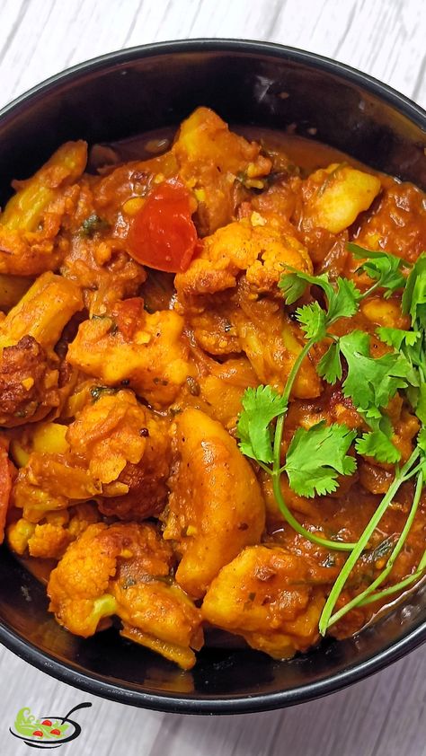 Aloo gobi sabzi prepared from potato and cauliflower served in a black bowl on white wooden table. the dish has medium pieces of veggies cooked with onion, tomatoes and other spices is served with coriander leaves topping! Sabji Recipe, Aloo Gobi, Food Video, Indian Recipe, Cooking Homemade, Food Carving, Delicious Donuts, Dinner Healthy, Homemade Dinner