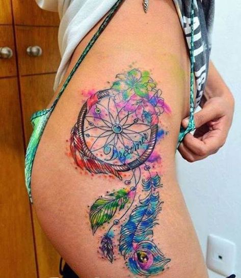 This tattoo manages to be extremely #colorful while also managing to be down to earth. It uses colors that are extremely rare when it comes to tattoos and that is exactly what this tattoo is all about. If you love your world to be as colorful as possible, this tattoo will go well with your outlook. #tattoofriday #tattoos #tattooart #tattoodesign #tattooidea Dreamcatcher Tattoo Thigh, Watercolor Dreamcatcher Tattoo, Wolf Dreamcatcher Tattoo, Dreamcatcher Tattoo Meaning, Atrapasueños Tattoo, Dream Catcher Tattoo Design, Tattoo Trend, Tattoo Zeichnungen, Muster Tattoos