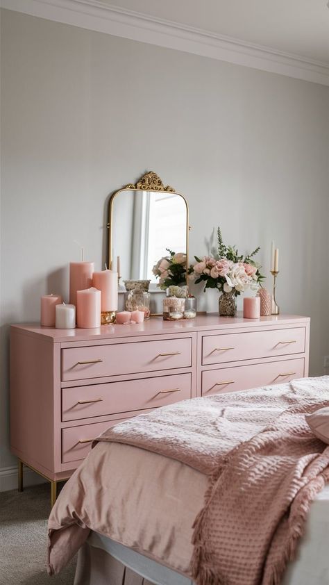 A soft blush pink dresser with gold handles, set against a light gray wall, adorned with delicate decor items like a gold-framed mirror, candles, and fresh flowers. Blush Pink Dresser, Bedroom With Dresser, Blush Pink Bedroom, Pink Dresser, Pink Bedroom Ideas, Unique Themes, Pink Bedrooms, Blush Tones, Bedroom Dresser