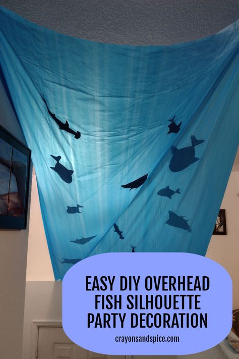 Picture of a blue tablecloth with fish silhouettes hanging over a staircase Aquarium Theme Party, Fish Party Theme, Under The Ocean Decorations, Diy Sea Themed Party Decorations, Under Water Birthday Theme, Underwater Party Ideas, Deep Sea Birthday Party, Diy Sea Party Decorations, Undersea Party