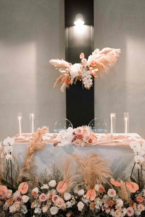 Sweetheart table with florals repurposed from the ceremony with pampas grass white orchids mauve roses and pink anthuriums at Hangar 12 in Orange County California Sharing An Orange, Florals With Pampas, Sweetheart Table Florals, Peach Wedding Colors, Mauve Roses, Brides Table, Table Florals, Modern Romantic Wedding, Grass Wedding