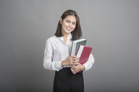 Beautiful teacher woman holding book on grey background Premium Photo Woman Holding Book, School Teacher Outfit, Teacher Picture, Teacher Outfits High School, Teacher Outfits Elementary, Spring Teacher Outfits, Summer Teacher Outfits, Teacher Outfits Fall, Teacher Photo