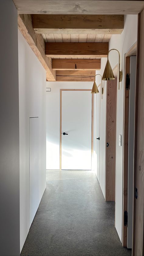 No trim here. This modern hallway features exposed timbers and door frames, flush doors with shadow gap reveals and a polished concrete floor. To top it off, handmade brass sconces amp up the cozy evening vibes. Timber Door Frame, Contemporary Hallway Doors, Modern Timber Frame, Hallway Sconces, Polished Concrete Floor, Contemporary Hallway, Shadow Gap, White Hallway, Evening Vibes