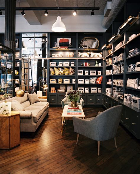 Exposed Ductwork - Gray built-in shelving surrounds a seating area Exposed Ductwork, Bookstore Design, Retail Lighting, Store Interiors, Retail Shelving, Showroom Design, Retail Store Design, Retail Interior, Store Interior