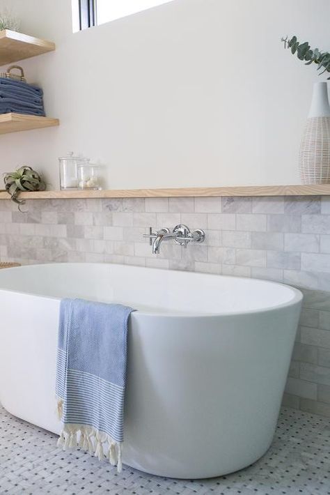 Half marble subway tiled wall in a cottage bathroom completed with a long oak floating shelf over an oval bathtub. Bathroom Trim, Tiled Tub, Master Addition, Tub Design, Oak Floating Shelves, Bathtub Walls, Primary Bath, Shower Floor Tile, Primary Bathroom