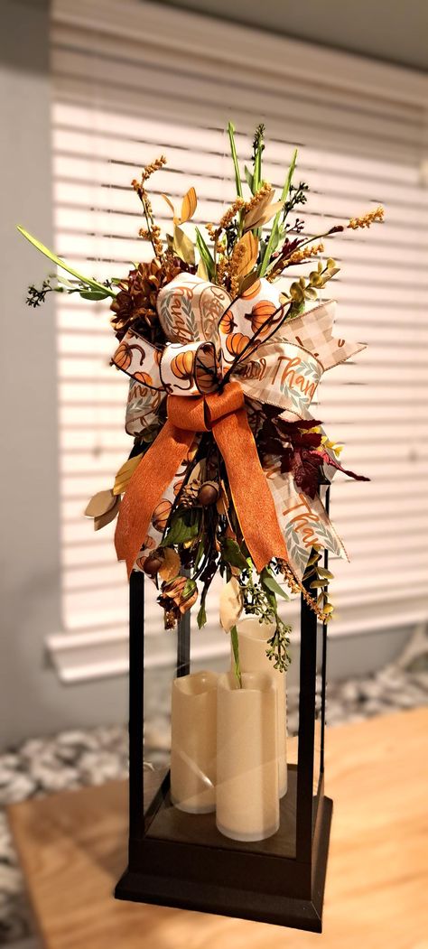 Add seasonal charm with a stunning Lantern Swag! Multiple fall options to choose from and each piece features a blend of rich, seasonal elements. Floral picks and leaves with luxurious flowers adds a touch of elegance. Each swag bring a natural, woodland feel, making either swag perfect for cozy fall decor. Layers of  wired ribbons with shades of orange, brown, yellow, green, and hint of blue add depth and texture. Ribbon colors will vary per piece design. Whether you're looking to adorn a lante Fall Decorated Lanterns Ideas, Fall Candlestick Arrangements, Fall Birdcage Decor Ideas, Fall Chandelier Decorations, Fall Lantern Ideas, Fall Floral Arrangements For Home, Lantern Decor Living Room, Fall Ladder Decor Ideas, Open Lantern Decor Ideas