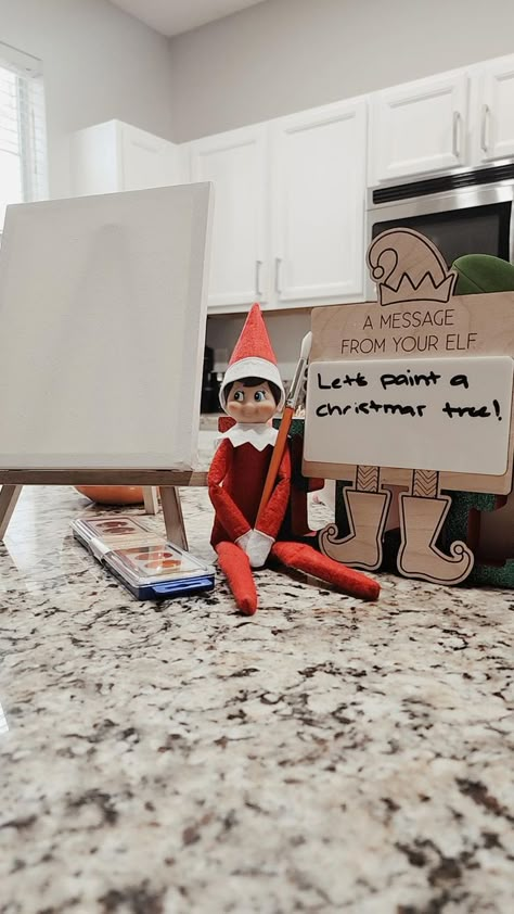 This Elf on the Shelf setup is such a cute and creative idea for a holiday activity! The elf is holding a brush with a message that says, "Let's paint a Christmas tree!" along with an easel, canvas, and paint palette. And the best part? You can find all these items at Dollar Tree, making it budget-friendly! This setup would definitely make a memorable morning surprise for little ones, sparking their creativity for the holiday season. Elf On The Shelf Painting, Paint A Christmas Tree, Shelf Painting, Elf On Shelf Ideas, Elf On Shelf, Elf Ideas, Creative Idea, Paint Palette, Elf On The Shelf Ideas