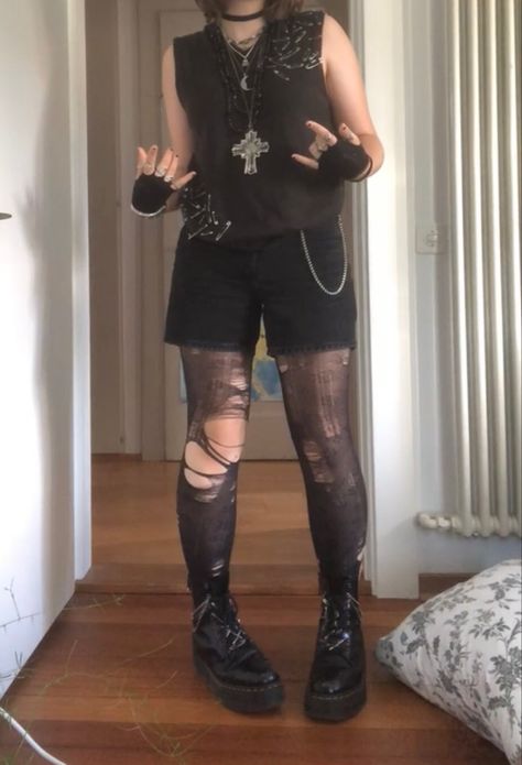 A mid-sized person/girl wearing a brown safety pin sweater vest with black shorts and patterned flower tights underneath, black fingerless gloves, black platform dr. Martens and multiple crystal rings and bracelets. 		The person is also wearing multiple silver necklaces. Dark Neutral Clothes, Summer Goth Masc, Goth Outfits Nonbinary, Dark Punk Outfits, Masc Goth Outfits Summer, Cute Masculine Outfits, Alt Outfits With Shorts, Grunge Androgynous Outfit, Punk Outfit Inspiration