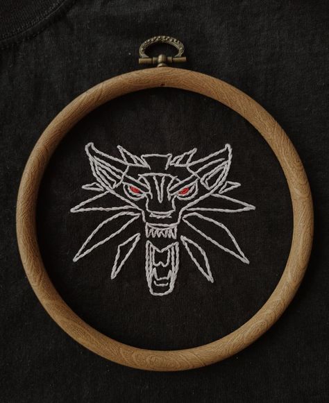 White Witcher logo (wolf with red eyes) embroidered on a black t-shirt Witcher Embroidery, Supernatural Embroidery, Witcher Wolf, Fantasy Logo, Wolf Logo, Simple Embroidery Designs, Hippie Home Decor, Mini Figurine, Simple Embroidery