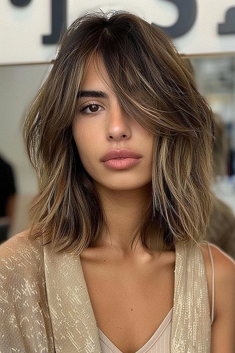 A woman with a textured long bob and side-swept bangs, showcasing choppy layers and balayage tones. Lob With Face Framing Layers Side Part, Long Bob With Side Swept Bangs, Textured Long Bob With Bangs, Bob Haircuts With Side Bangs, Lob For Thick Hair, Bob With Side Swept Bangs, Haircuts With Side Bangs, Cut Side Bangs, Textured Long Bob