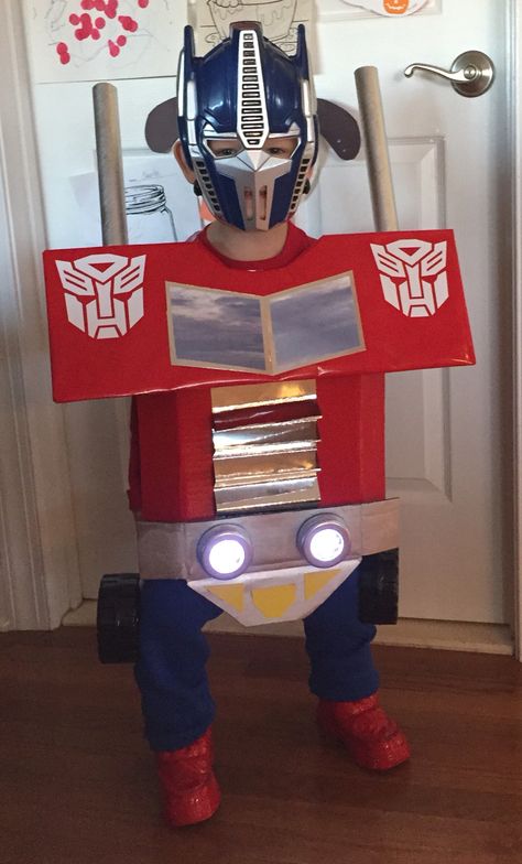 DIY Transformers Optimus Prime Costume. Cardboard boxes, shiny scrap-booking paper, dollar store click light and a bunch of spray paint went into making this costume. I used Velcro and elastic to secure the costume to my 3 year old. The mask was purchased at Party City for $1.99 Truck Costume Diy, Optimus Prime Costume Kids, Optimus Prime Costume Diy, Truck Costume, Optimus Prime Costume, Transformer Costume, Transformers Rescue Bots, Like Father Like Son