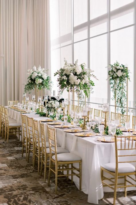 Head Table Decor Wedding, Green Plant Table Decor Wedding, White Table Cloth Wedding With Greenery, Tall White And Green Centerpiece Wedding, Wedding Head Table Ideas, White And Green Sweetheart Table Flowers, Wedding Head Table, Green And White Cocktail Table Flowers, Gold Chivari Chairs