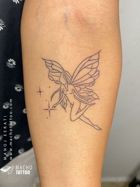 A photo of a tattoo on someone’s arm. The tattoo is of a fairy with wings and a dress. The tattoo is done in black ink and is in an outline style. The tattoo is located on the upper arm near the shoulder. The background is a black and white floral pattern. There is a watermark on the image that reads “MACHO TATTOO www.machotattoo.com”. The tattoo was done by Macho Tattoo, a professional tattoo studio in Hyderabad that offers a wide range of services and styles. Geometric Lion Tattoo, Tattoo Black And White, Black And White Outline, Lipstick Tattoos, Pineapple Tattoo, Tiny Wrist Tattoos, Becoming A Tattoo Artist, Fairy Tattoo Designs, Moon Tattoo Designs