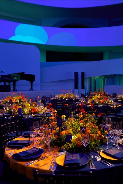 The table setting and scenography for the Guggenheim International Gala's dinner transformed the museum into a fantastical garden. Projections of flowers in an electric blue hue contrasted with the warmly lit tables for a colorful display of lights. From an aerial view, the Dior Maison table settings give the illusion that they are flowers themselves with illuminated centerpieces. © Reed Young Corporate Event Centerpieces, Dinner Table Set Up, Dinner Table Centerpieces, Dinner Party Table Settings, Gala Themes, Corporate Dinner, Garden Centerpiece, Lighted Centerpieces, Gala Party