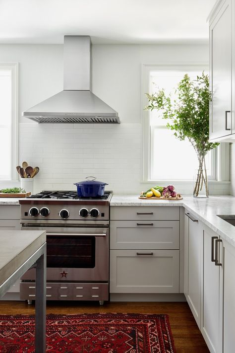 Transitional kitchen with white cabinetry, white countertops, and white subway tile backsplash. Kitchen Design Stainless Steel, Wood Flooring In Kitchen, Range Hood White, Kitchen No Upper Cabinets, White Subway Tiles Kitchen Backsplash, Flooring In Kitchen, White Subway Tile Kitchen, No Upper Cabinets, Freestanding Kitchen Island