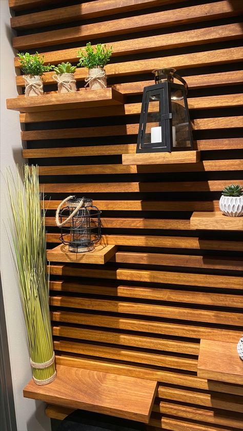 This wall design, made from black Valcromat and Iroko, brings not only nature & warmth into any room, it also can serve as a shelving unit. #walldesign #wooddesign #shelvedesign #woodwall #interiordesign Slat Wall With Moveable Shelves, Wood Slat Shelf Wall, Outdoor Wall Shelf, Wood Slate Accent Wall With Shelves, Slate Wall With Shelves, Horizontal Wood Slat Wall With Shelves, Wood Panel Wall With Shelves, Wood Slat Wall Horizontal, Horizontal Wood Slat Wall Bedroom