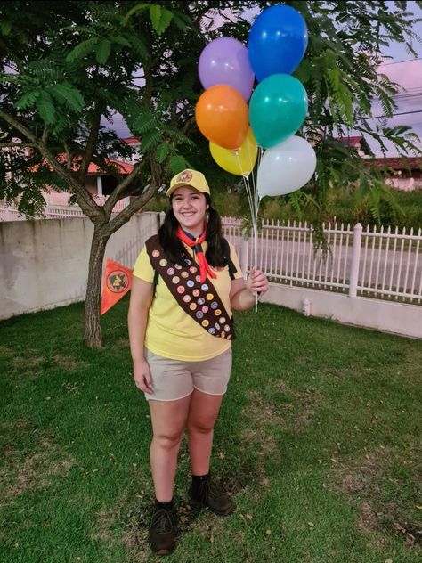 she's wearing a yellow shirt, brownish shorts, combat boots, a brown ribbon full of scout badges and she's holding balloons Russel Costume, Russell Up Costume, Russell Costume, Russel Up, Bike Night, Movie Character Costumes, Up Movie, Up Costume, Diy Costume