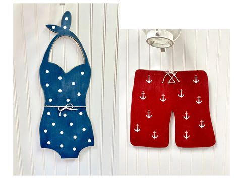 These unique cottage wall hangings are a perfect addition to your pool house, cottage or lake house! The retro wood bathing suits measure 23" and 14" tall. These large bathing suites will add a splash of happy to your home! They also make great front porch decor, use as your door hanger to welcome your visitors! The bathing suit is painted navy blue, the swim trunks are painted red, both are distressed for that rustic touch and decorated with a twine bow. Made out of premium 1/2 inch birch plywo Swimming Pool Bathroom Ideas, Nautical Decor Diy, Cottage Wall Art, Beach Wall Hanging, Lake House Gifts, Unique Cottages, Twine Bow, Art Door, House Lake