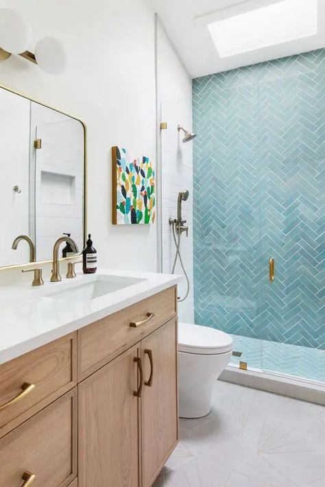 Picture of a cool modern bathroom with a skylight, a shower space with turquoise herringbone tiles, a stained vanity and brass fixtures Herringbone Shower Tile Accent Wall, Bathroom With Light Blue Tile, Blue White Bathroom Tile, Blue And Oak Bathroom, Bathroom Blue Tile Wall, Blue Tile Accent Wall Bathroom, Blue Accent Tile Shower Wall, Bathroom Herringbone Tile Wall, White Bathroom With Blue Accents