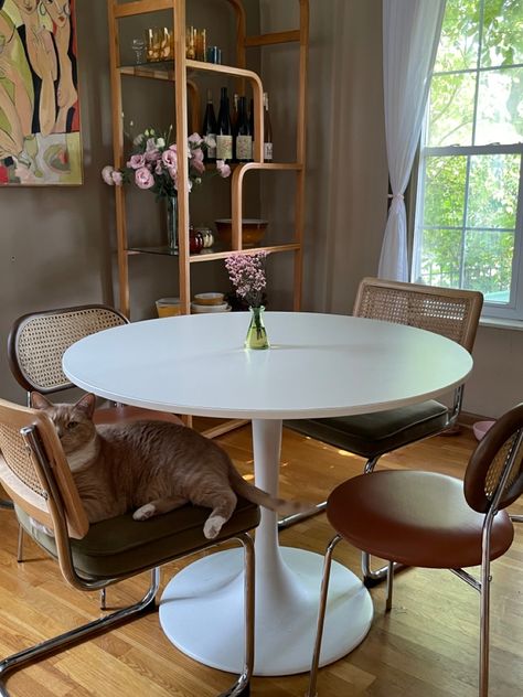 Small space retro mid century modern dining room with white tulip table. Ikea docksta table with cesca chairs Round Table Dining Room White, Tulip Table Dining Room Ideas, Tulip Dining Table Decor, Dinner Table Small Apartment, Round Dining Table With Mismatch Chairs, White Circle Table Dining Rooms, Round Tulip Dining Table, Tulip Table Styling, Tulip Table Mismatched Chairs