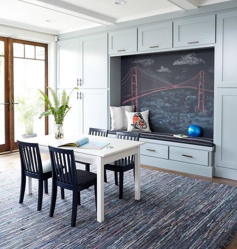 Gray contemporary homework and playroom features a wall lined with gray built in cabinets accented with bronze pulls and positioned framing a built-in gray bench topped with a black cushion fixed against a large chalkboard. Cabinets Playroom, Built In Reading Nook, Homework Station Ideas, Storage Playroom, Den Library, Chalkboard Wall Bedroom, Homework Room, Homework Station, Library Office