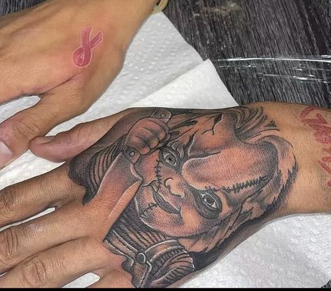 Chucky Tattoo On Hand, Chunky Hand Tattoo, Hood Arm Tattoos, Chucky Tattoo Hand, Small Hand Tattoo Ideas For Men, Black Male Hand Tattoos, Hand Tattoos For Black Guys, Black Men Neck Tattoo Ideas, Hood Hand Tattoos