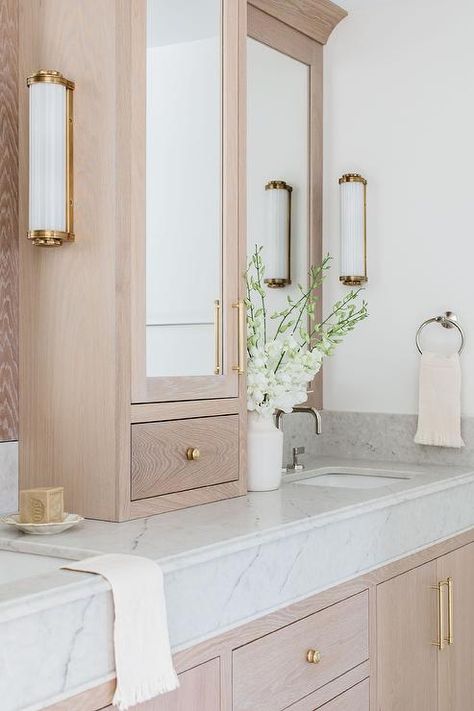 White Oak Bathroom Vanity Brass Hardware, White Double Vanity Bathroom Master Bath, White Oak Master Vanity, Bath Mirror Light, Center Vanity Cabinet, White Oak Bathroom Vanity Gold Hardware, White Marble Bathroom Vanity, Master Bath With Cabinet Between Sinks, Primary Bath Vanity