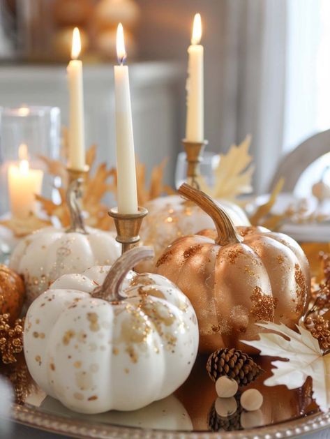 For a sophisticated and festive centerpiece, look no further than this glittering pumpkin arrangement. Gold and white pumpkins, dusted with sparkling accents, are beautifully complemented by tall, slender candles. The warm glow of the candles reflects off the shimmering pumpkins, creating a luxurious and inviting atmosphere. This centerpiece is perfect for an elegant fall dinner party, adding a touch of glamour and enchantment to your table decor. White And Gold Pumpkins, Modern Thanksgiving Tablescapes, White Pumpkins Wedding, Fall Bridal Shower Ideas, Glam Fall Decor, Fall Candle Centerpieces, White Pumpkin Centerpieces, Pumpkin Tablescape, Pumpkin Table Decorations