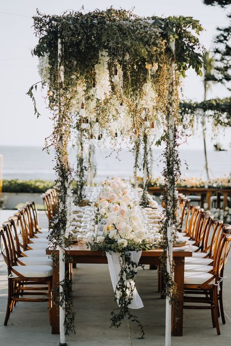 ROMANTIC HANGING TABLE DECOR WITH WHITE WISTERIA, GREEN LEAVES ON AN INDUSTRIAL LIGHTING STRUCTURE Over Table Hanging Decorations, Planning A Small Wedding, Dinner Reception, White Wisteria, Hanging Table, Table Wedding, Long Table, Hanging Flowers, Industrial Lighting