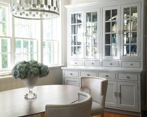 Classic white and gray dining room features an oval mid-century pedestal dining table seating two gray curved back nailhead dining chairs lit by a Worlds Away Leona Pendant. Benjamin Moore Pale Oak, Gray Dining Room, Breakfront Cabinet, Banquette Ideas, Pale Oak, Dream Dining Room, Dining Room Cabinet, Transitional Dining Room, Grey Dining Room