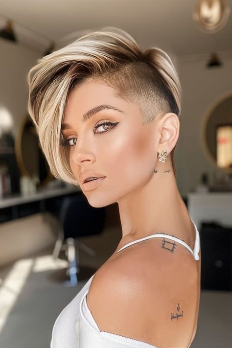 This Fall Haircut showcases a bold undercut paired with voluminous blonde highlights, creating a striking contrast. The undercut offers a sharp, edgy vibe, while the long, highlighted top adds a touch of glam. This style is perfect for those looking to combine elegance with a bit of rebellion this fall. Short Hairstyle Women With Shaved Side, Short Bob Undercut Hairstyles, Short Hairstyle Women Shaved Sides, Short Pixie Cut Styles, Pixie Undercut Hairstyles, Female Undercut, Long Pixie Cut With Bangs, Female Short Hairstyles, Short Undercut Hairstyles