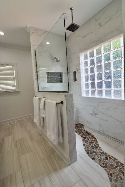 This master bath has a curbless shower with river pebble accents running through the floor. It has a linear drain, rainhead shower, and two niches. See more at https://makeovermybath.com/bathroom-remodeling/bathroom-design/ Shower With Linear Drain, Rainhead Shower, Kitchen And Bathroom Remodeling, Budget Bathroom Remodel, Linear Drain, Diy House Renovations, Kitchen Bathroom Remodel, Bathroom Remodel Designs, Complete Bathrooms