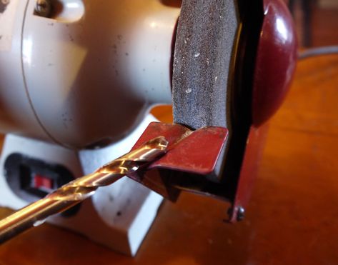 Most bench grinders have a tool rest with a groove in the surface that is preset to engage a drill bit with the wheel at exactly the 31° angle that twist bits require/. Drill Bit Sharpening, Woodshop Tools, Drill Bit Sharpeners, Bench Grinders, Forstner Bit, Woodworking Power Tools, Bench Grinder, Sharpening Tools, Project Board