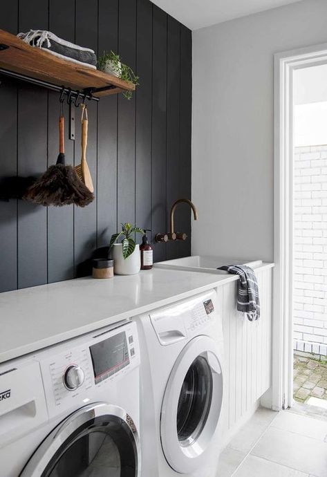 a contrasting laundry with a black shiplap wall, a white shiplap cabinet, white appliances and a countertop plus a door to the garden Laundry Shelves, Chic Beach House, White Laundry Rooms, Stylish Laundry Room, White Laundry, Laundry Room Renovation, Laundry Design, Laundry Room Shelves, Modern Laundry Rooms