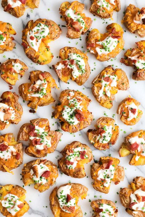 top view of a batch of loaded smashed potatoes that are covered in sour cream, cheese and bacon bits. Loaded Smashed Potatoes, Homemade Guac, Baked Potato Bar, Potato Bar, Teriyaki Meatballs, Dried Potatoes, Loaded Baked Potato, Smashed Potatoes, Bacon Bits