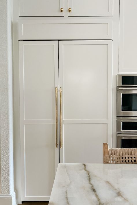 Looking for ideas for a built-in fridge? This refrigerator blends seamlessly into the cabinets and also makes a statement with brass hardware. Click here to see more kitchen design ideas from this project! Beautiful Kitchens Refrigerator, Built In Column Fridge And Freezer, Refrigerator Handles Gold, Refrigerator That Looks Like Cabinets, Refrigerator Built In Cabinet, Refrigerator Next To Wall, Fridge In Cabinet, Fridge Built In Cabinet, Built In Refrigerator Ideas