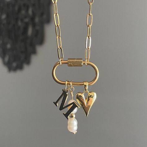 The Keepsake Necklace features a personalized initial charm and a convenient carabiner to easily add any other favorite charms you have. This necklace serves as a special container for all your cherished memories through charms. Featuring: Openable Carabiner with a Gold Plated Stainless Steel Initial Charm, a Long Pearly Charm, & our 18k gold plated Dainty Heart charm. The necklace is 16 inches long. Although this piece is made with water resistant materials, we always recommend to take pieces o Chunky Necklace Gold, Gold Charms For Necklace, Carabiner Charm Necklace, Dainty Charm Necklace, Chunky Cross Necklace, Personalized Jewelry For Mom, Boyfriend Jewelry, Memory Necklace, Carabiner Necklace