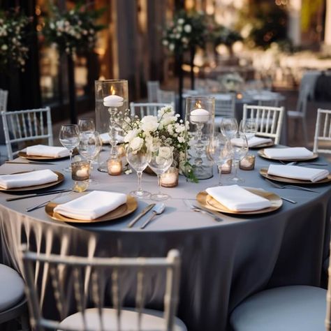 Amp up the elegance of your outdoor wedding space by setting up riveting tablescapes. Dress up the tables in a silver polyester tablecloth and arrange gold chargers, white napkins, gold cutlery, & wine glasses for a chic place setting. Ooze warm romantic glow by displaying gold mercury votive candle holders along with glass crystal cut candle holders gracefully placed inside glass vases. Create a stunning white hued rose & baby breath flower centerpiece to heighten the elegance of the tabletops. Silver Mercury Glass Centerpiece, Mercury Glass Centerpiece, Round Table Centerpiece, Wedding Votives, Baby Breath Flower, Table Candles, Party Decorations Table, Wedding Space, Silver Candle Holders