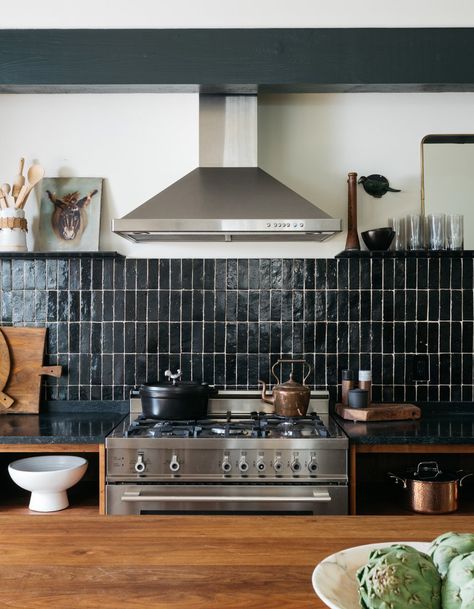 The dark countertop is a unique choice to add to this kitchen, but the light reflecting off of the tiles allows it to floe. The stainless steel, black, warm brown and white all work well together. Black Kitchen Backsplash, Soapstone Counters, Black Backsplash, Emily Henderson, Black Tiles, Butcher Block Countertops, Black Kitchen, Kitchen Photos, Black Kitchens