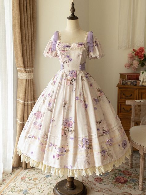 One piece and jumper skirt depicting wisteria purple and red wisteria flowers and white butterflies. The flowers and butterflies, which look like they were painted in watercolor, have an elegant atmosphere. The butterflies fluttering around in search of sweet flower nectar are beautiful, yet somehow ephemeral. We have two types of dresses and one type of jumper skirt. There are two types of dresses: (A)_1002 One type comes with a ribbon choker that makes your neck look gorgeous, and the other ty Purple Flower Dress, White Butterfly Dress, Neat Dress, Gaun Abad Pertengahan, Wisteria Purple, Old Fashion Dresses, Ribbon Dress, Jumper Skirt, Butterfly Dress