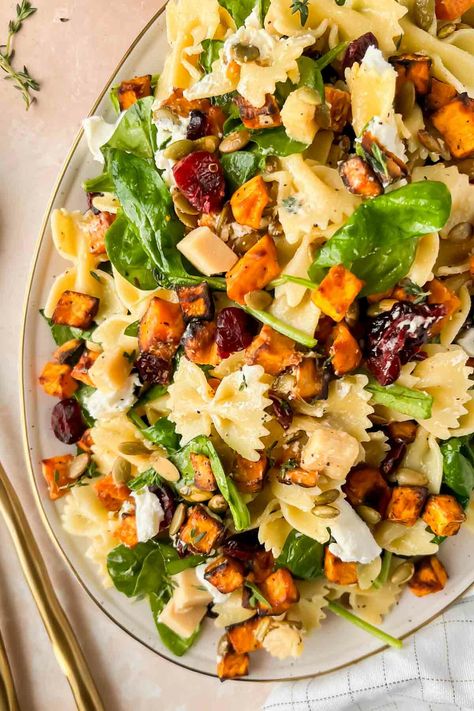 "Looking for a 30 minute recipe that is clutch for Thanksgiving, Friendsgiving, or Christmas? This is it. A fall salad loaded with roasted sweet potatoes, dried cranberries, sharp cheddar cheese, and bow-tie pasta. It feels like comfort food, without the heaviness of typical holiday foods. This easy fall harvest pasta salad convinced my fiance that ‘spinach actually is good’ – and that’s a mic drop for the delicious Maple vinaigrette dressing that coats this perfect fall salad. The Harvest Pasta Salad, Maple Vinaigrette Dressing, Thanksgiving Pasta, Fall Pasta Salad, Harvest Pasta, Fall Pasta, Maple Vinaigrette, Thanksgiving Potluck, Fall Salad