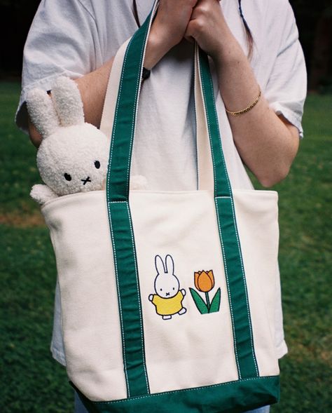 Our miffy market tote is perfect for carrying everything you love! It features 3 pockets (2 interior zipper pockets and 1 exterior pouch pocket) that allow you to organize it perfectly. Our favorite new feature we have never included in a bag before is an interior keychain strap so that your keys will never get lost in the bottom of your bag again! This, and the rest of our brand new miffy collection will be available on 6/14 at 2pm PST. #miffy #bunny #nijntje Miffy Tote Bag, Miffy Merchandise, Miffy Collection, Miffy Bunny, Keychain Strap, Okayama, Just Peachy, Market Tote, A Bag