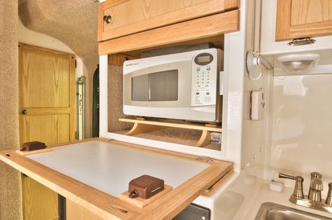 The Sharp microwave oven sits on a shelf and is held in place by a web strap.  Paper plate and other miscellaneous storage under microwave.  A little LED light turns ON when the compartment door is opened, this helps reading the buttons and the readout on the microwave oven.  The downward-opening door is faced with Formica so that it can serve as yet another work surface in the "kitchen" area. Rv Remodel Ideas, Casita Camper, Casita Trailer, Casita Travel Trailers, Wet Bath, Microwave Cabinet, Rv Lighting, Small Trailer, Aluminum Siding