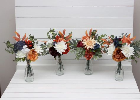 These gorgeous centerpieces feature a mix of warm autumn hues like burnt orange, ivory, and deep burgundy, accented by touches of eucalyptus and blue berries. Perfect for adding a rustic, cozy feel to your wedding or special event! 🍂✨ #AutumnWedding #RusticCenterpiece #FauxFlowers #WeddingDecor #FallDecor #Centerpieces #weddingflorist Bouquet Fall Wedding, Ivory Bouquet, Faux Bouquet, Mini Bouquets, Boho Wedding Flowers, Gorgeous Centerpieces, Groom Accessories, Faux Flower Arrangements, Burgundy Flowers